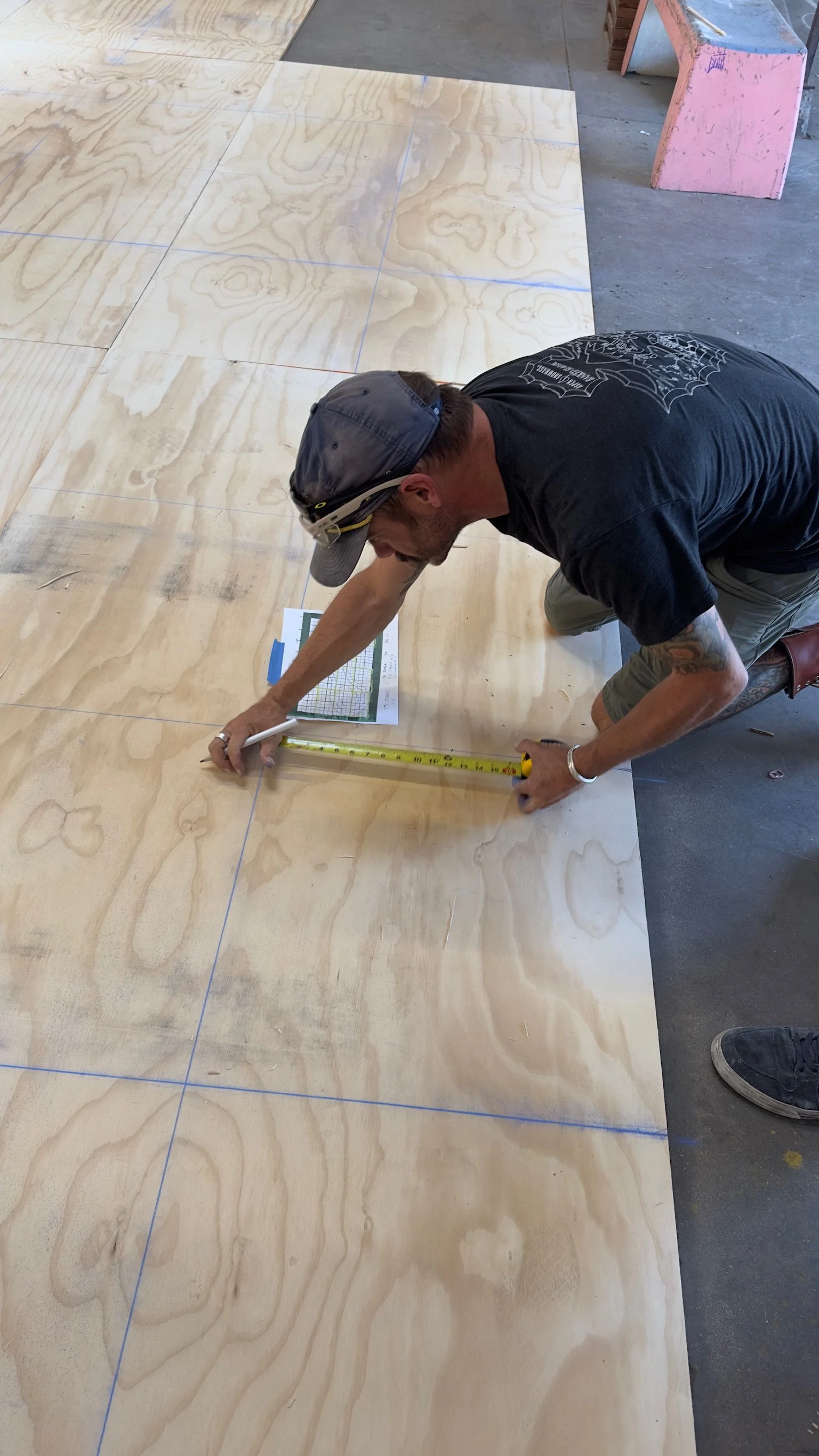 A craftsman marking and measuring plywood for the structure