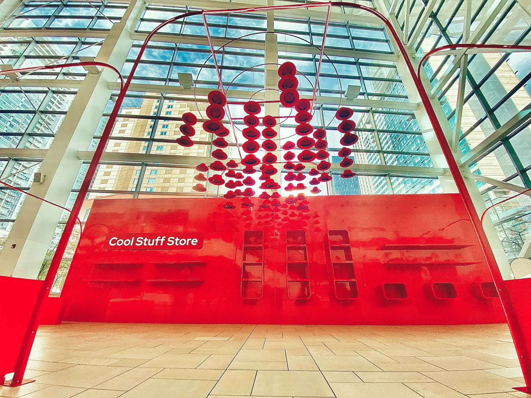 Red hats suspended above the Cool Stuff Store at Red Hat Summit 2024