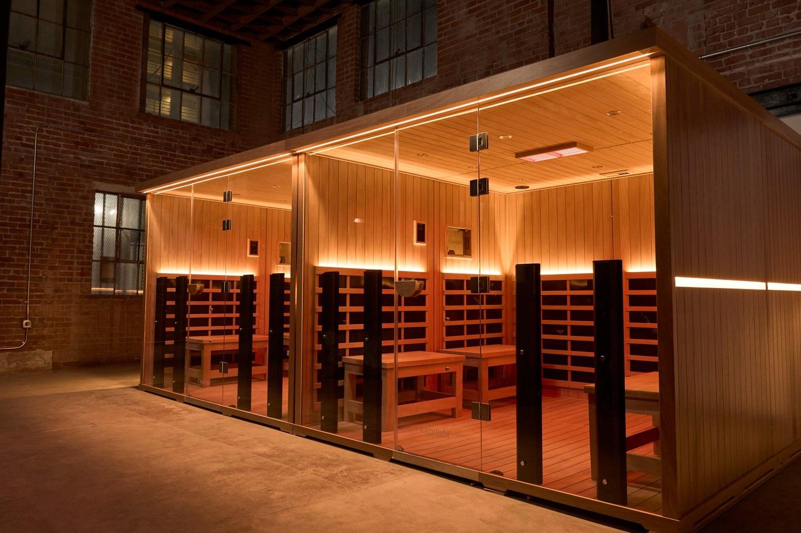 Glass enclosed infrared sauna suite glowing warm against exposed brick inside Heroic