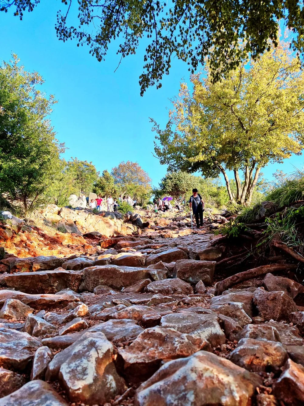 Pilgrims climbing the rocky path of Apparition Hill in Međugorje