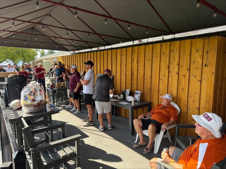 Former players catching up on the clubhouse patio by the raffle baskets