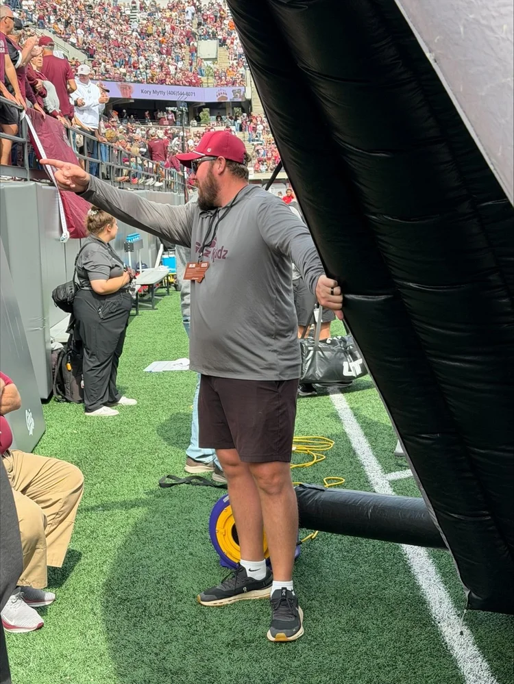 Game-day crew on the sideline by the inflatable tunnel