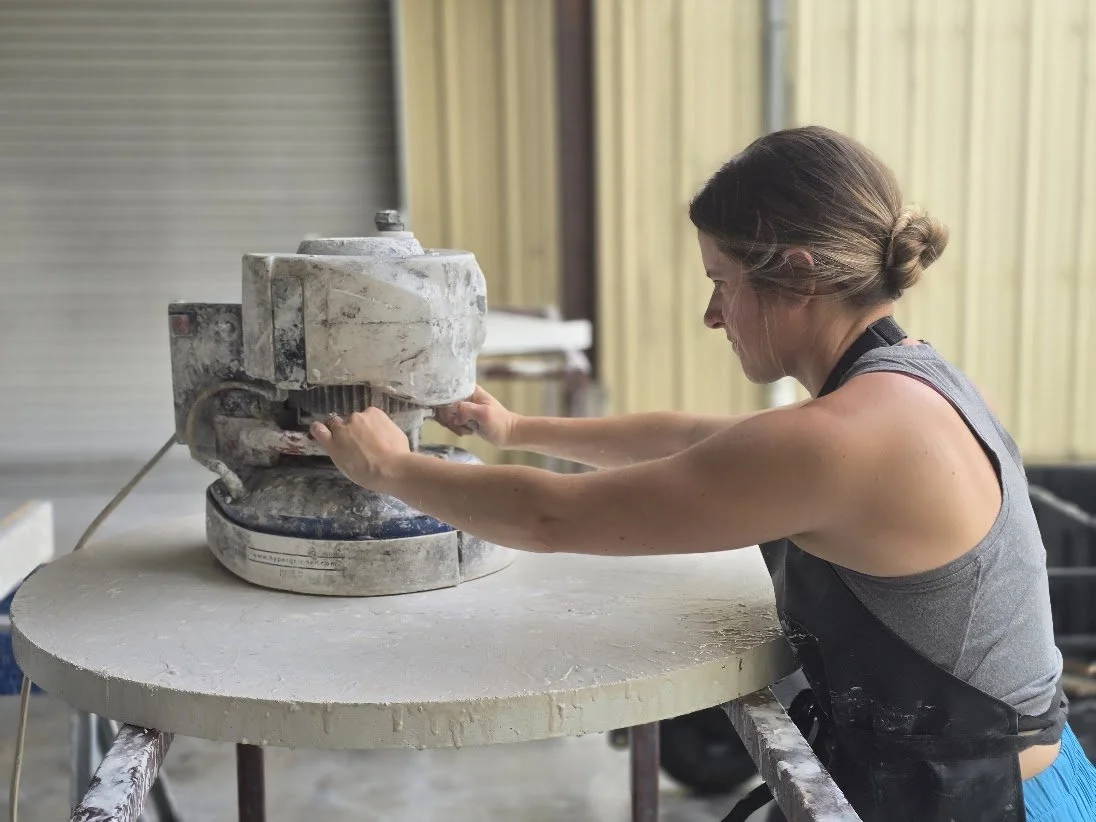 Rachel operating a polisher across a round Calhoun tabletop