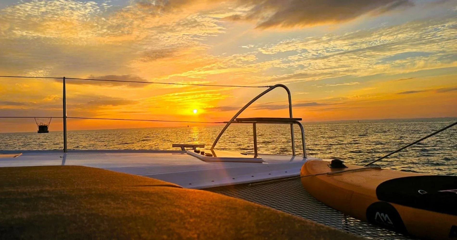 Deck des Segelkatamarans Lucia 40 bei einem goldenen Sonnenuntergang auf offener See