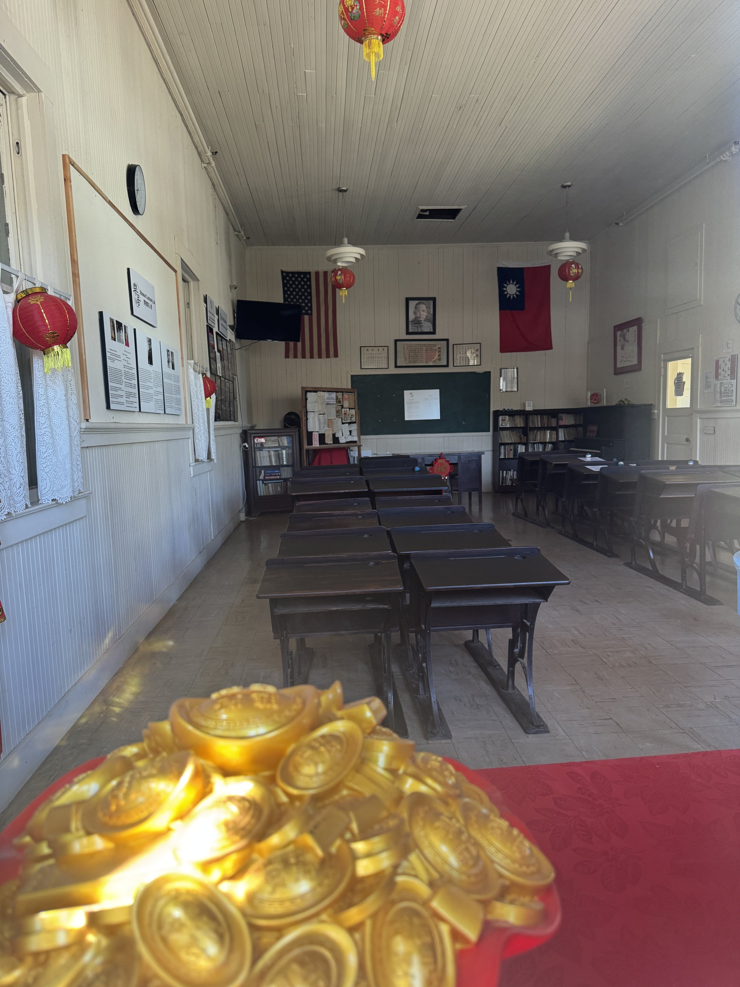 Historic Chinese school classroom in Locke with wooden desks, lanterns, and American and Taiwanese flags.
