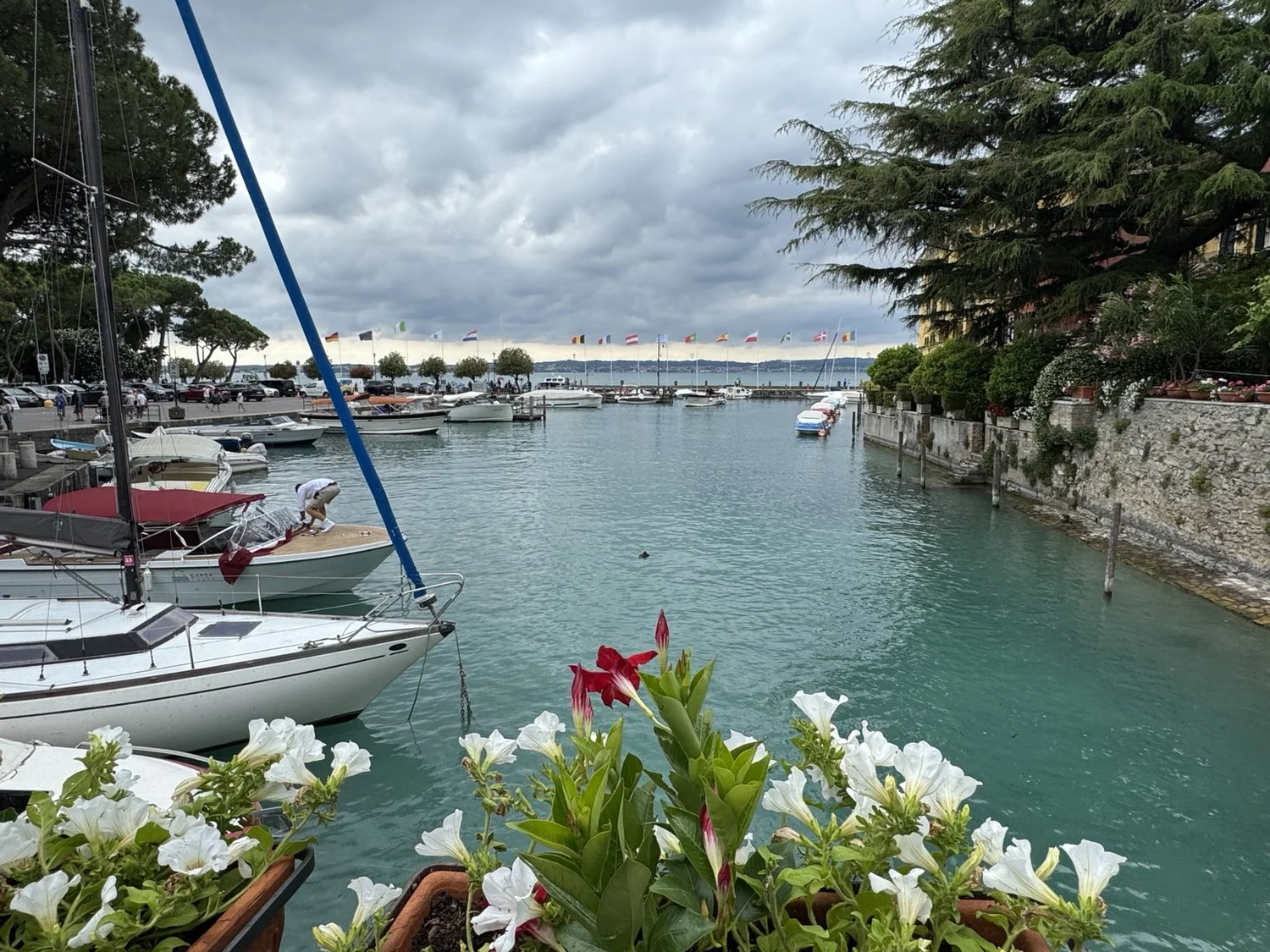 Sailboats, flowers and turquoise water in Sirmione harbor on Lake Garda