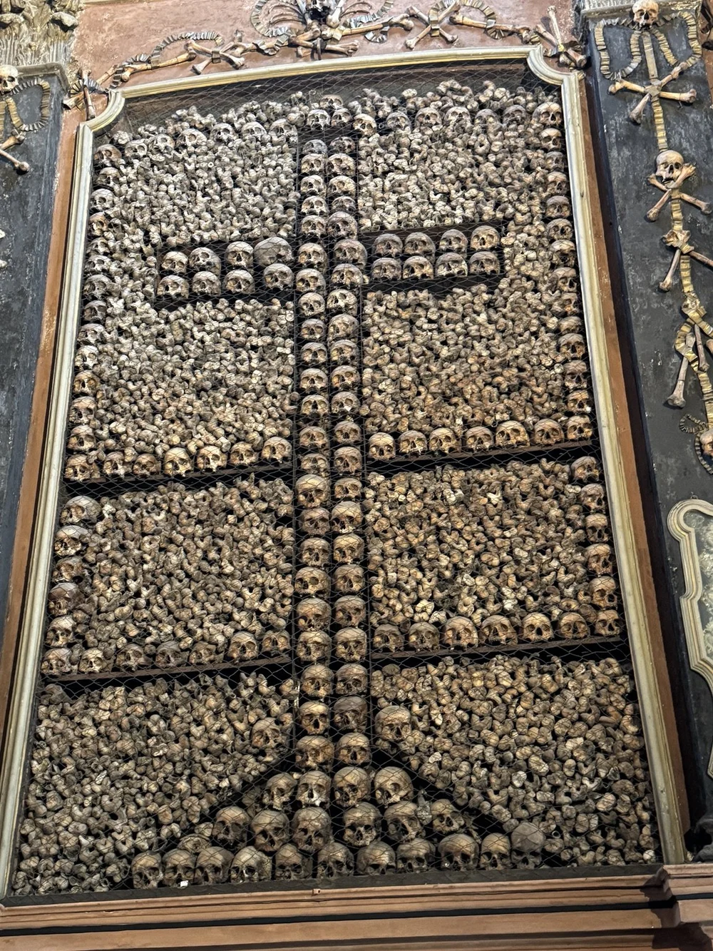 Human skulls and bones arranged in geometric patterns at San Bernardino alle Ossa ossuary in Milan