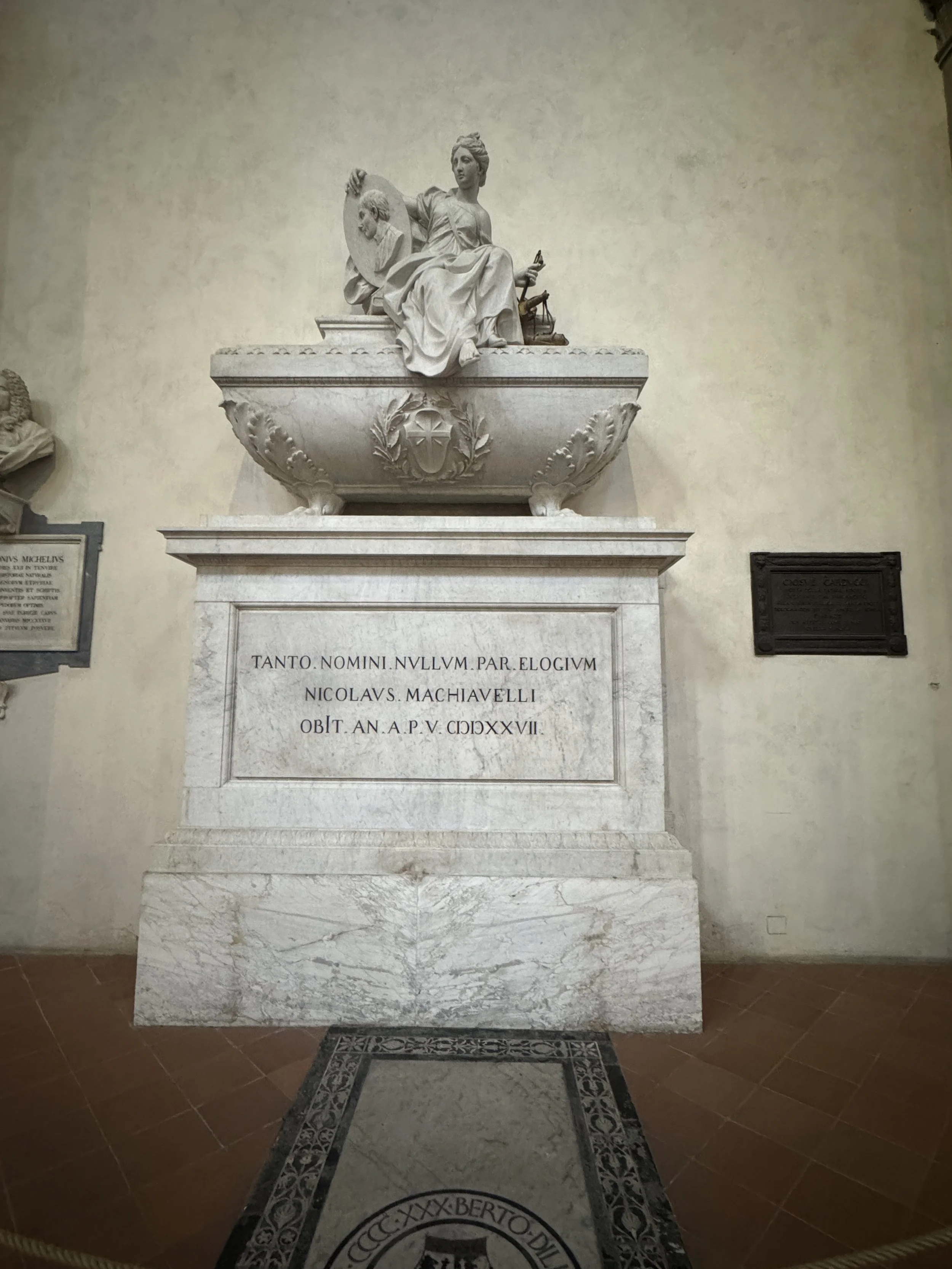 Marble memorial with a seated sculpture inside the Basilica di Santa Croce.