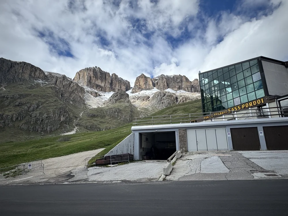 Sass Pordoi cable car station beneath rugged, snow-dusted Dolomite cliffs.