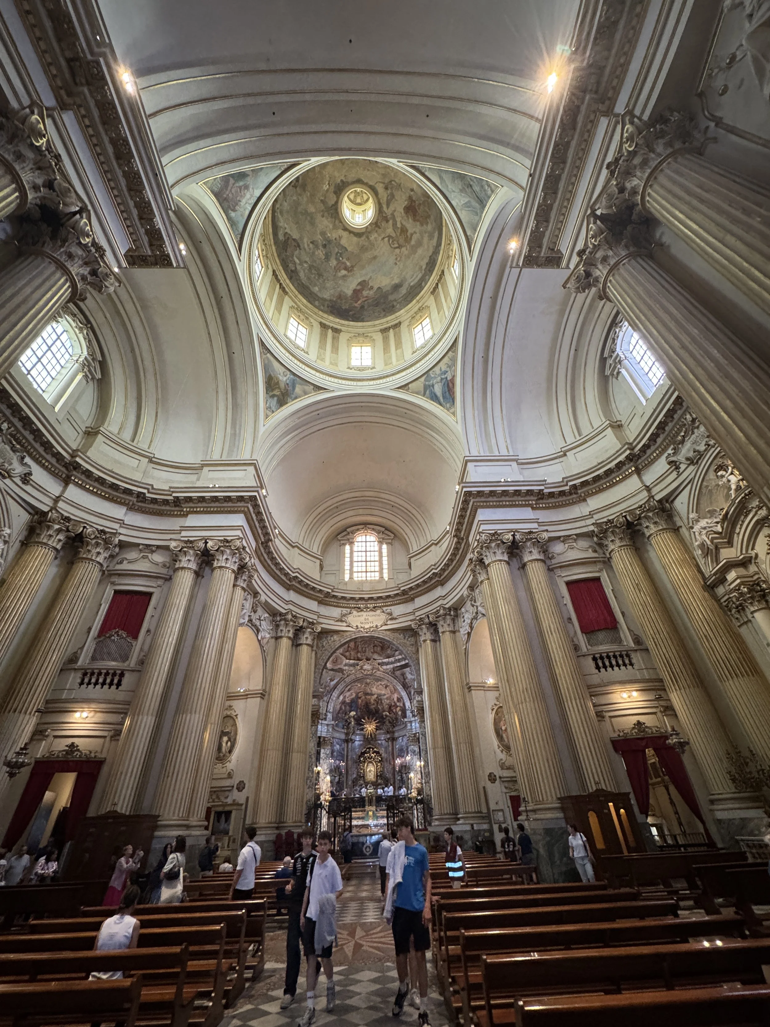 Grand interior of the Sanctuary of the Madonna di San Luca with its dome, columns and illuminated altar.