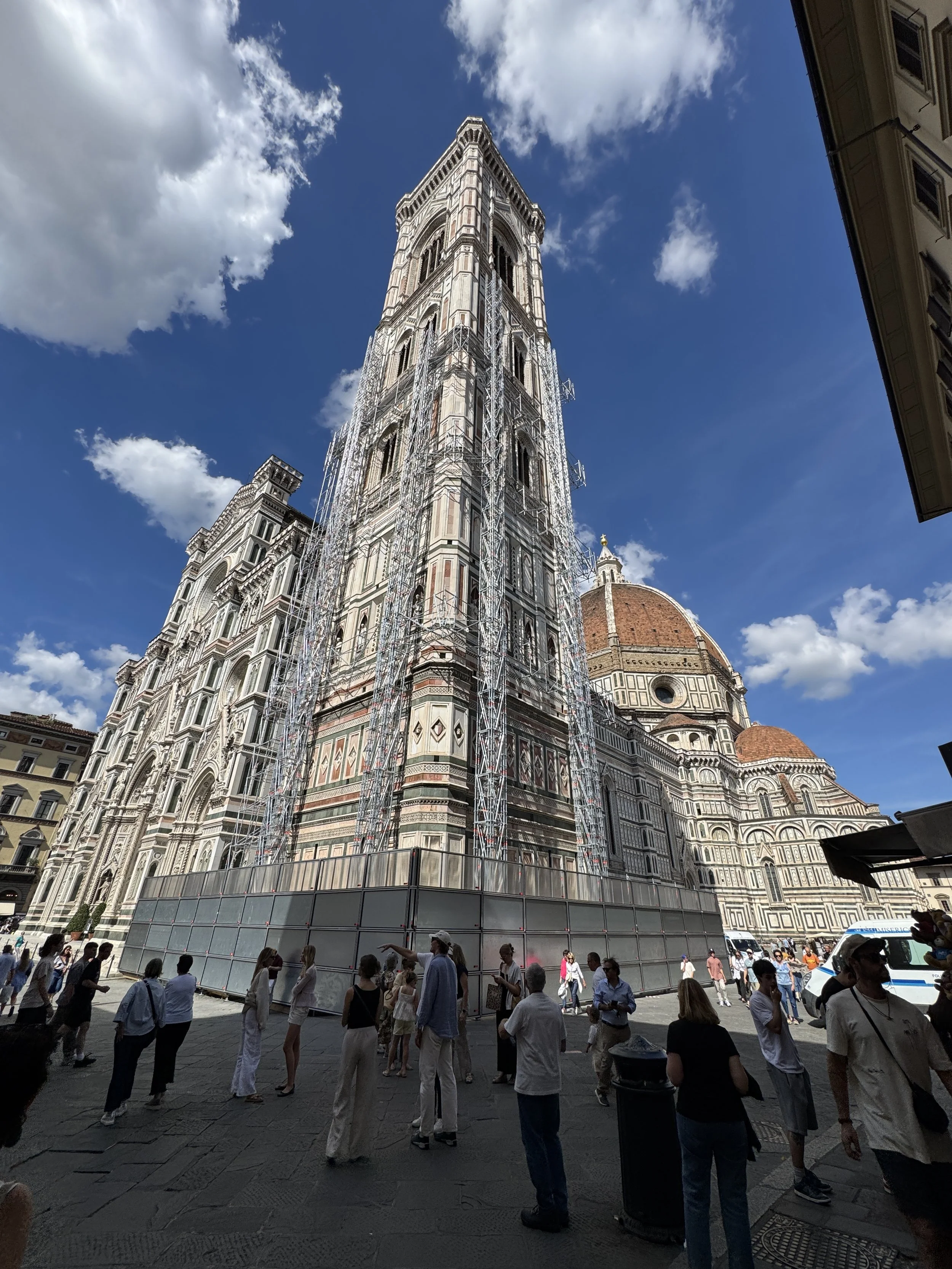 Giotto’s Campanile and the richly decorated Florence Duomo beneath a partly cloudy sky.