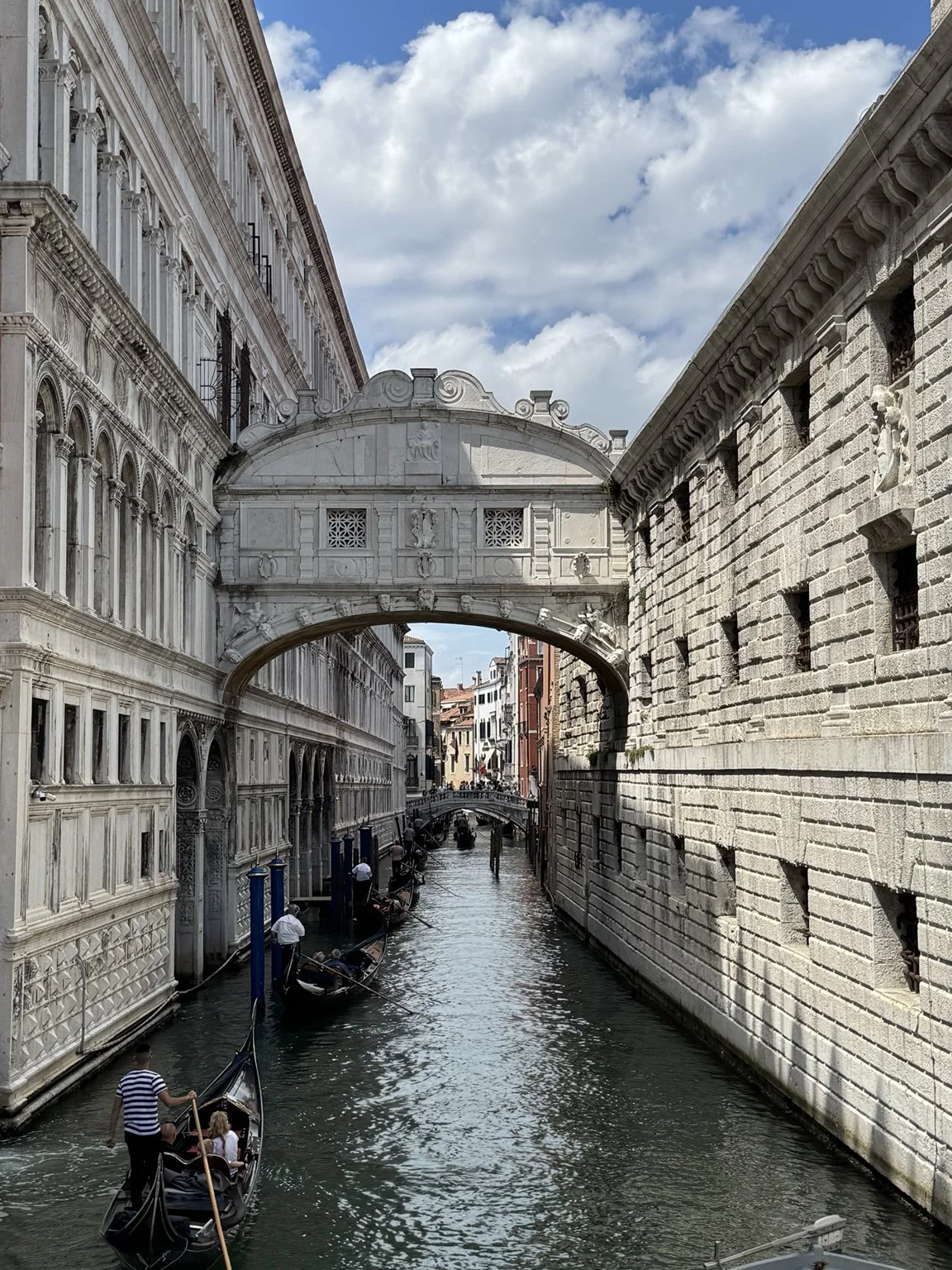 Bridge of Sighs spanning a narrow Venetian canal with gondolas below.