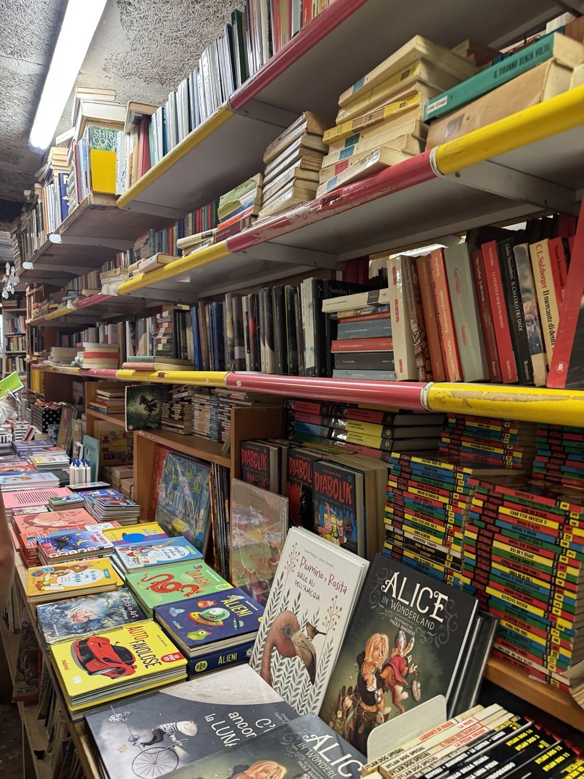 Crowded shelves and tables filled with colorful books inside Libreria Acqua Alta.