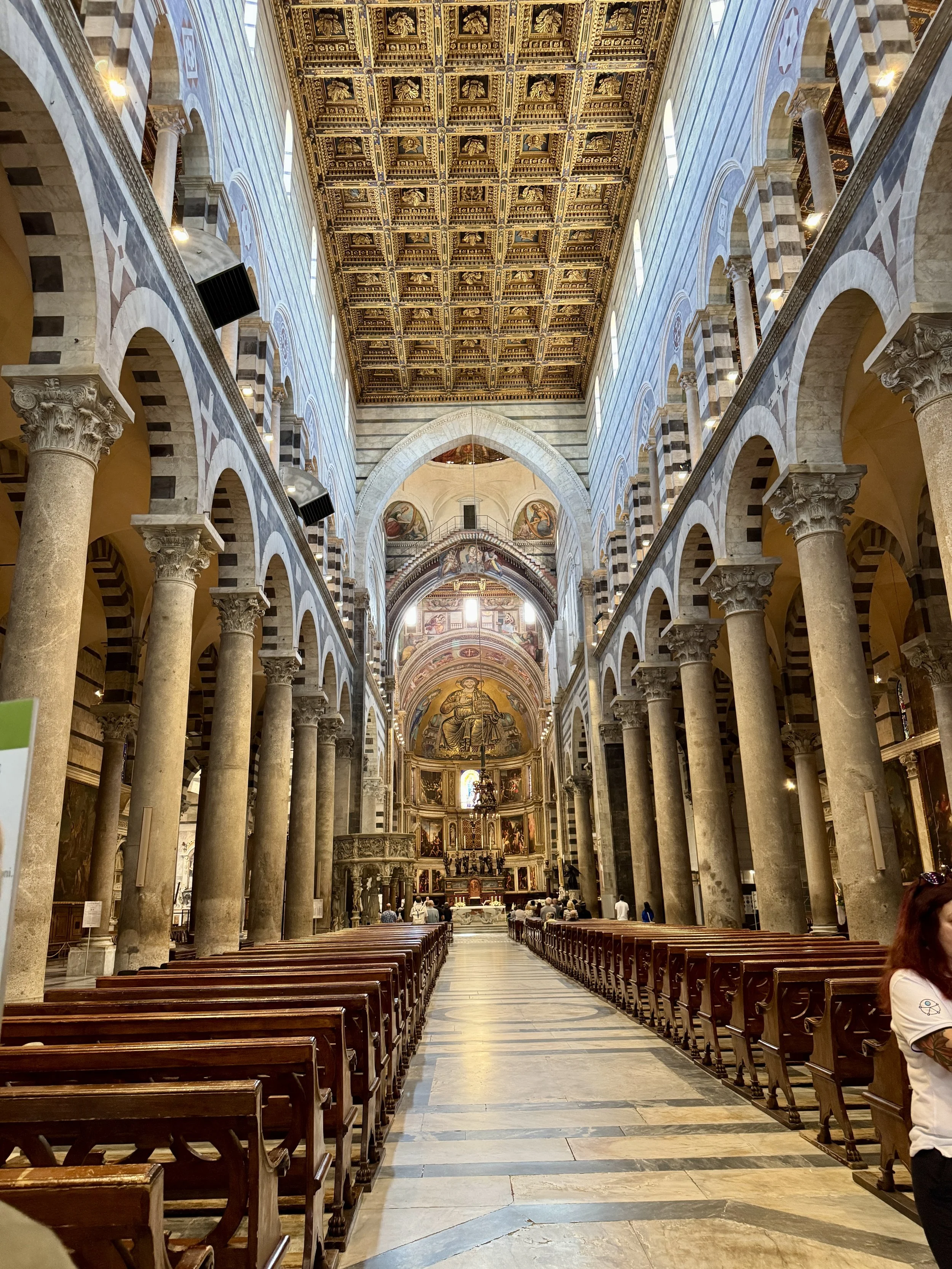 Ornate nave, striped marble arches and gilded ceiling inside Pisa Cathedral.