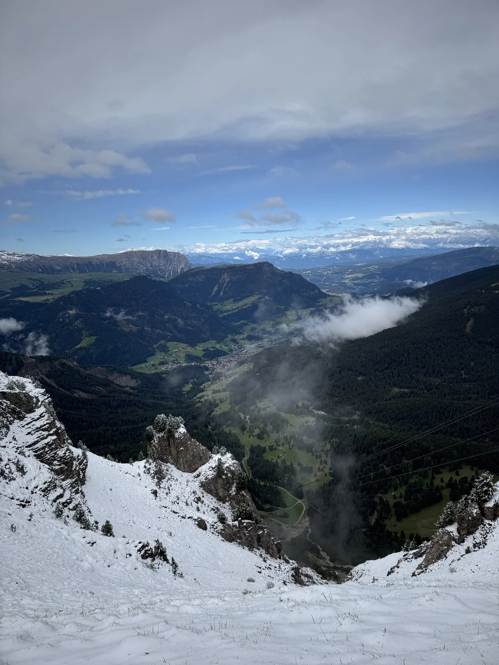 Snow-covered Seceda slope overlooking Val Gardena and the cloud-wrapped Dolomites.