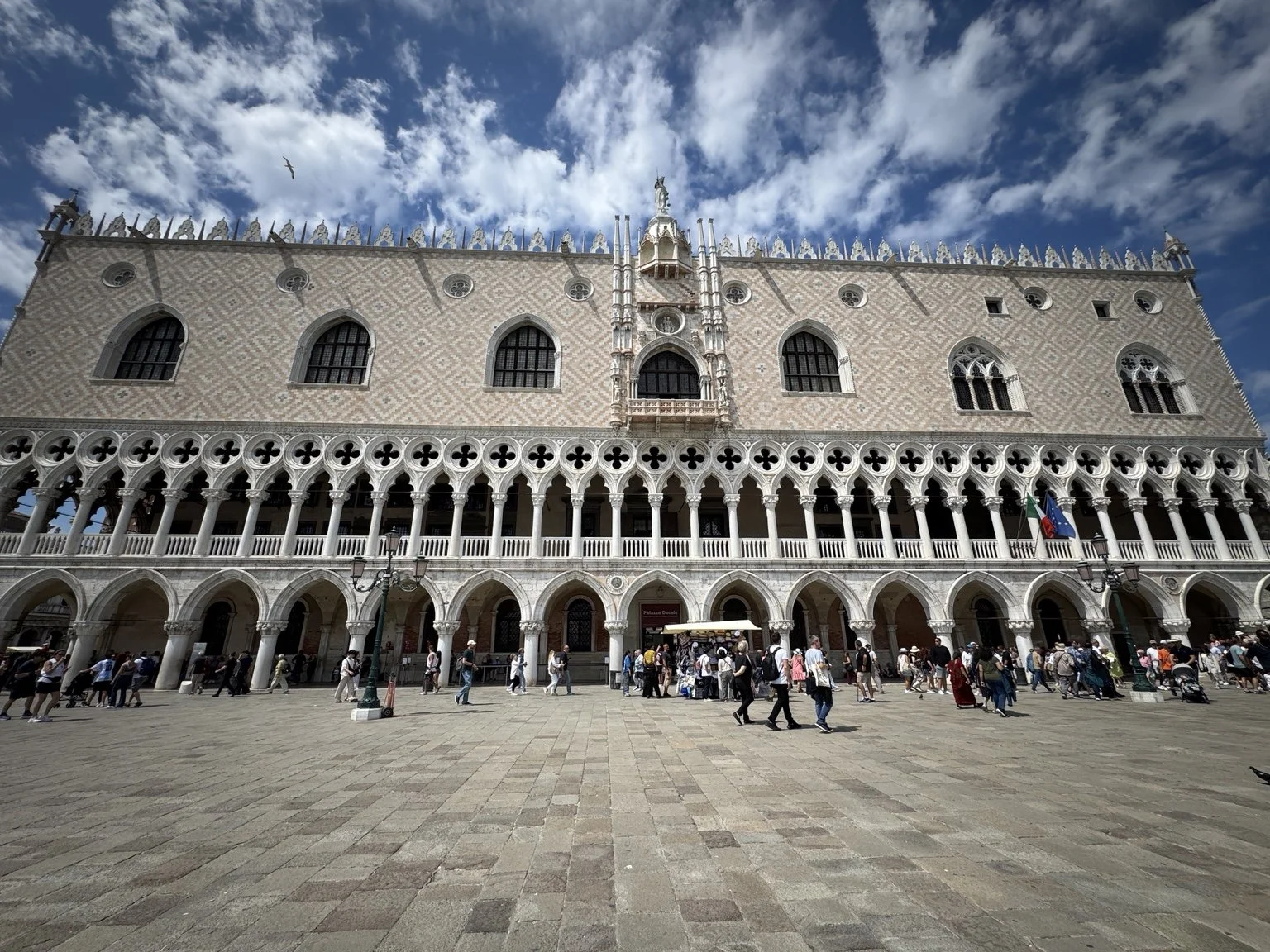 Gothic façade and arcades of the Doge’s Palace beneath a vivid blue sky.