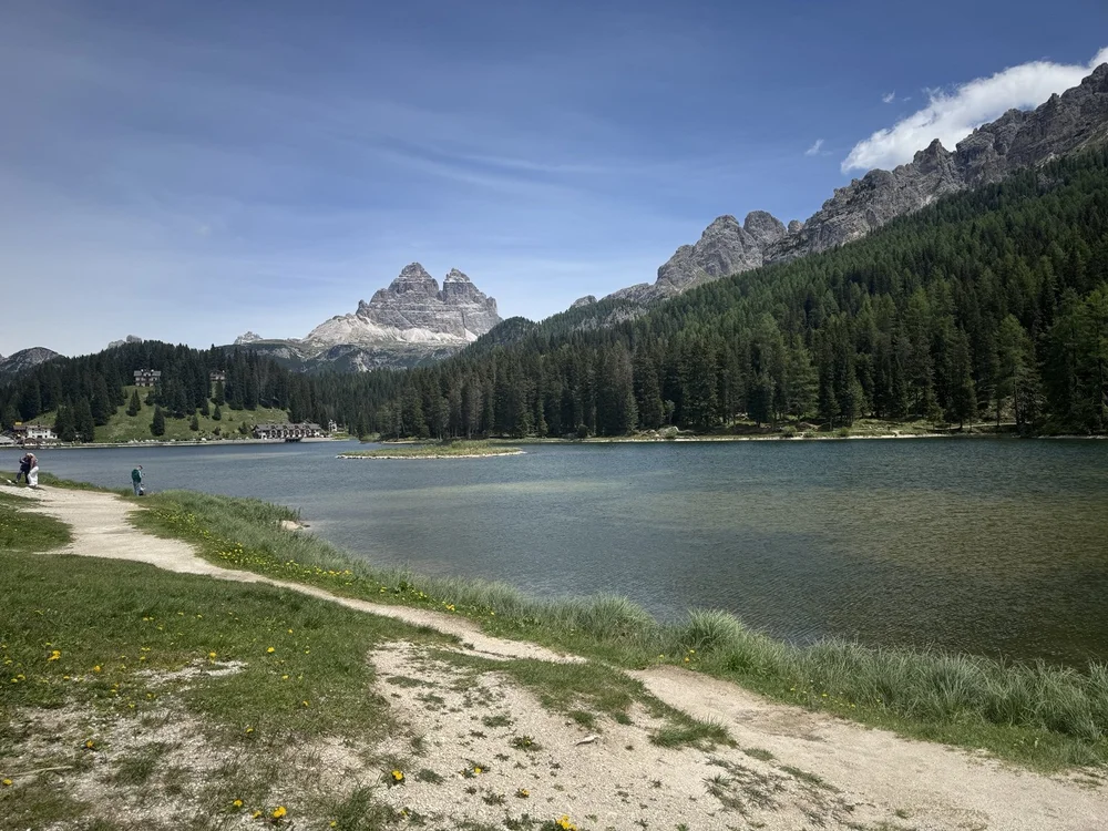 Lago di Misurina framed by evergreen forest with Tre Cime di Lavaredo in the distance.