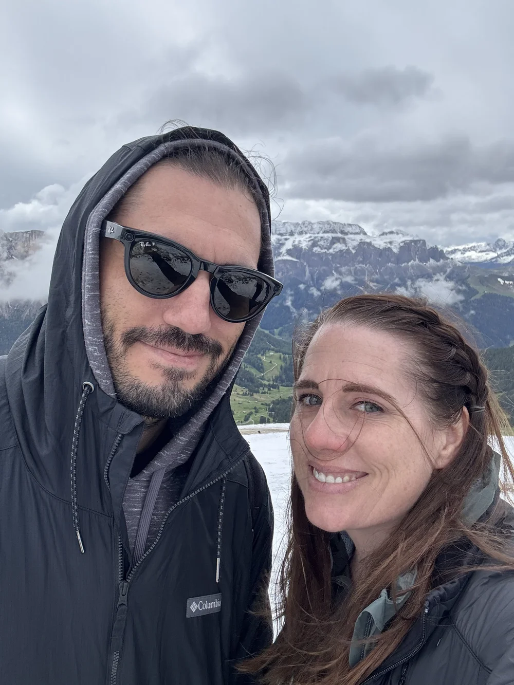 Couple at the snowy Seceda summit with the Dolomites behind them.