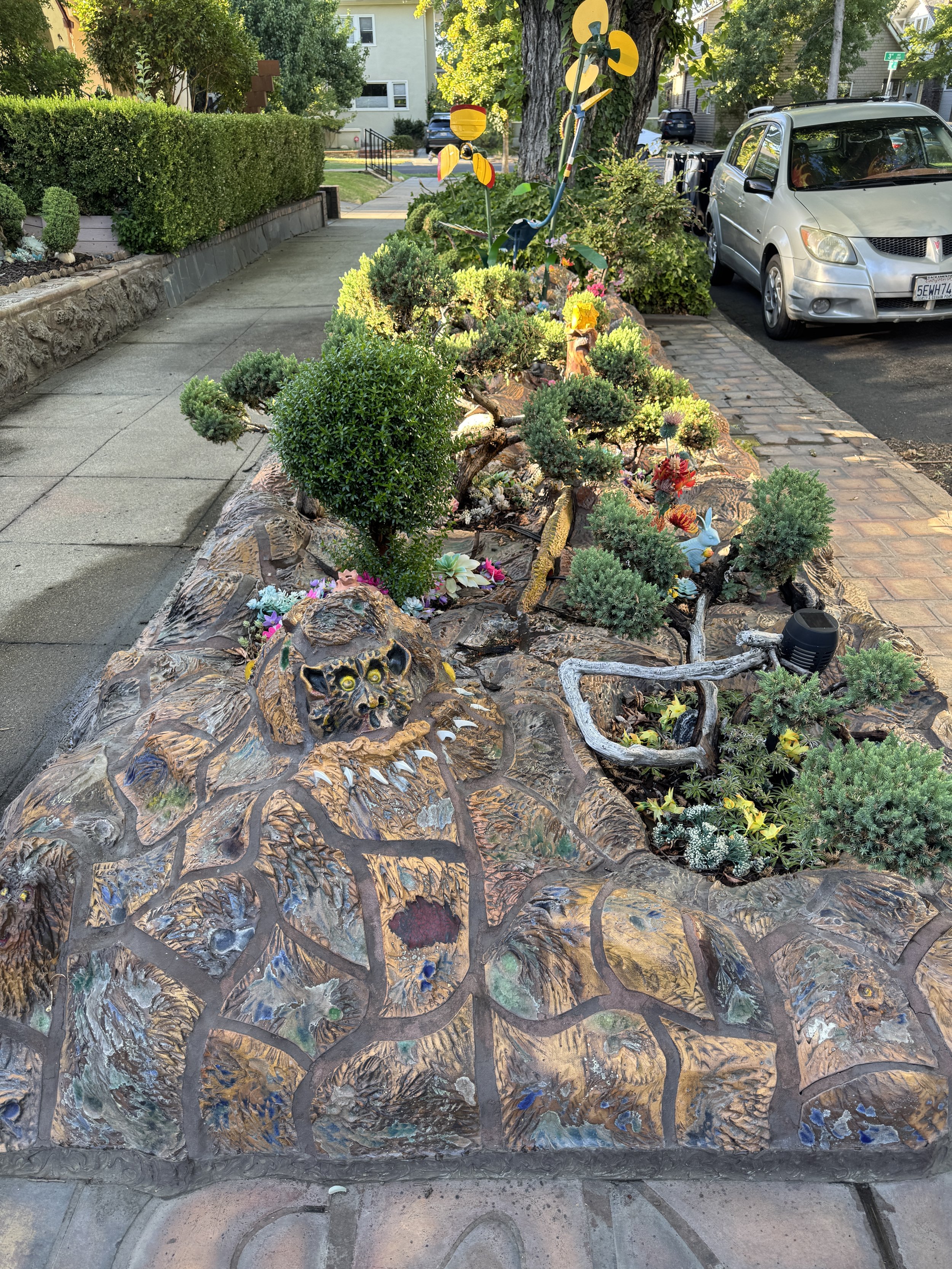 Detailed sculpted garden wall filled with small creatures, plants, and colorful decorations at the Dragon House.