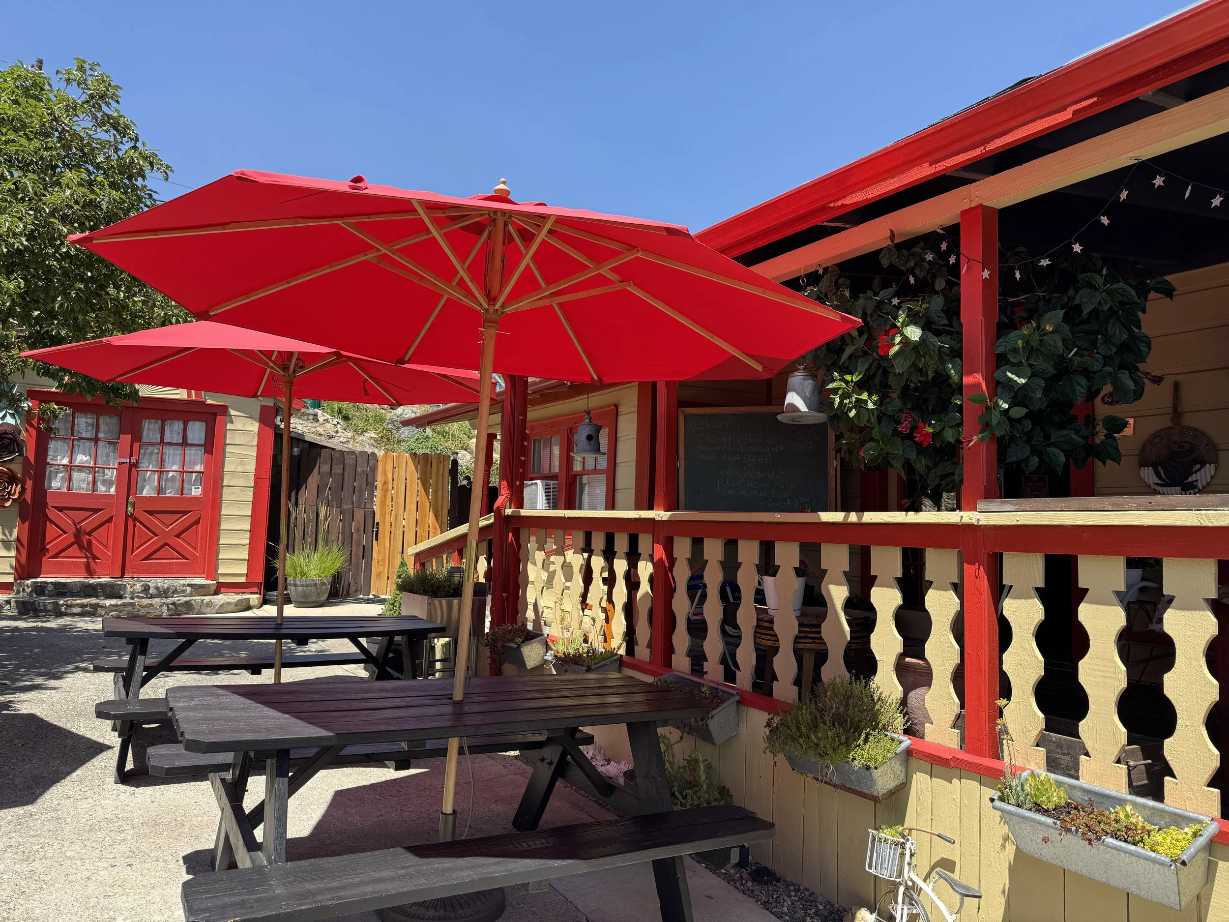 Sunny outdoor patio with red umbrellas at the Cider House at Canvas Café in Virginia City, Nevada.