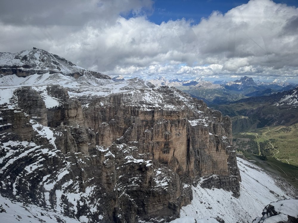 Snow-covered rocky plateau and distant Dolomite peaks viewed from Sass Pordoi.