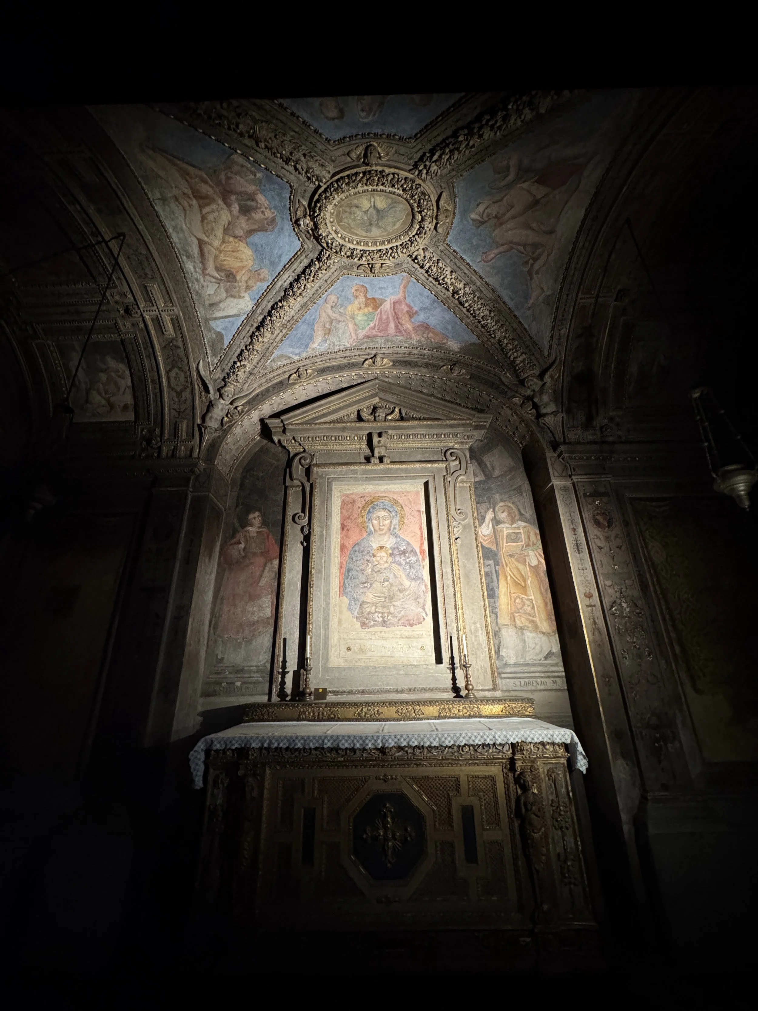 Dimly lit frescoed chapel and altar inside the Basilica di Santo Stefano.
