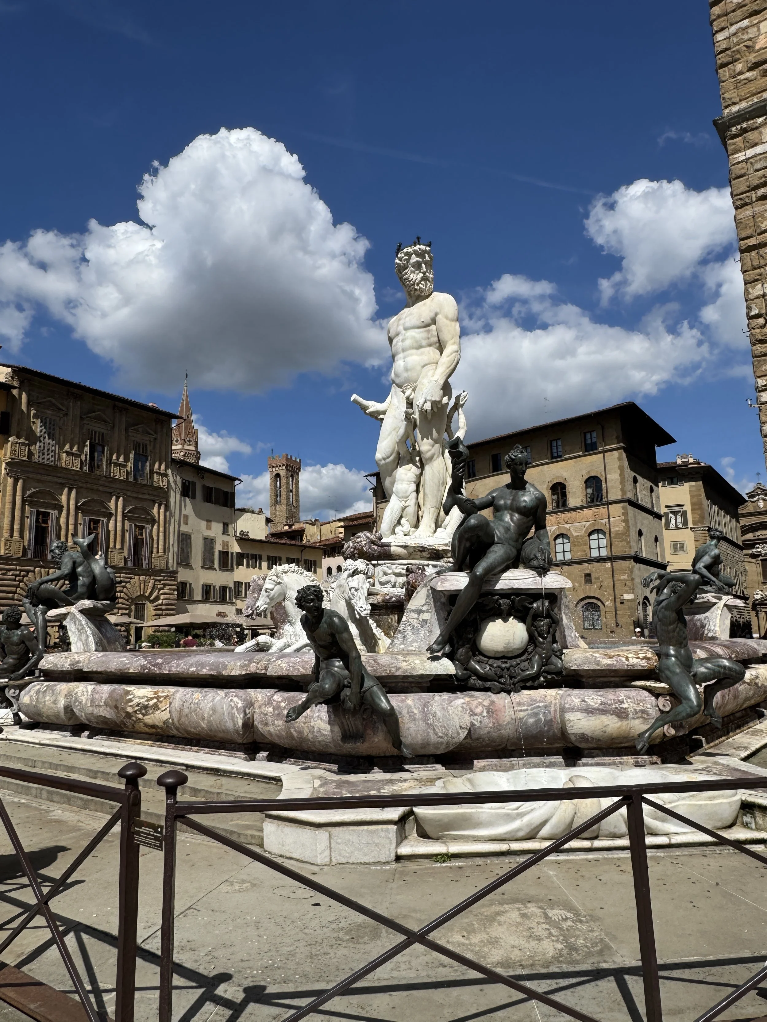 Monumental marble sculpture beneath a bright blue Florence sky.