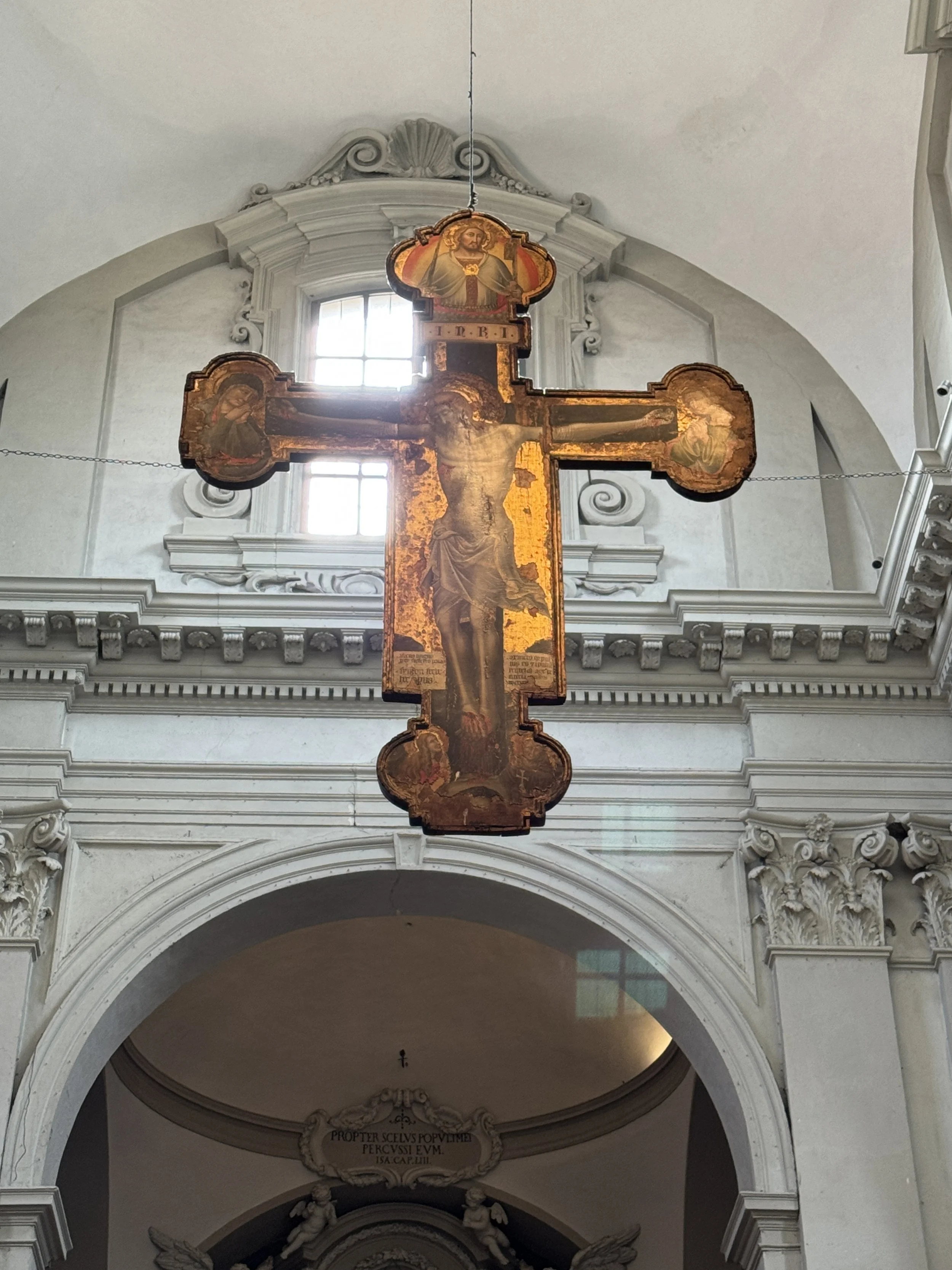 Historic painted crucifix displayed inside the Basilica di Santo Stefano complex.