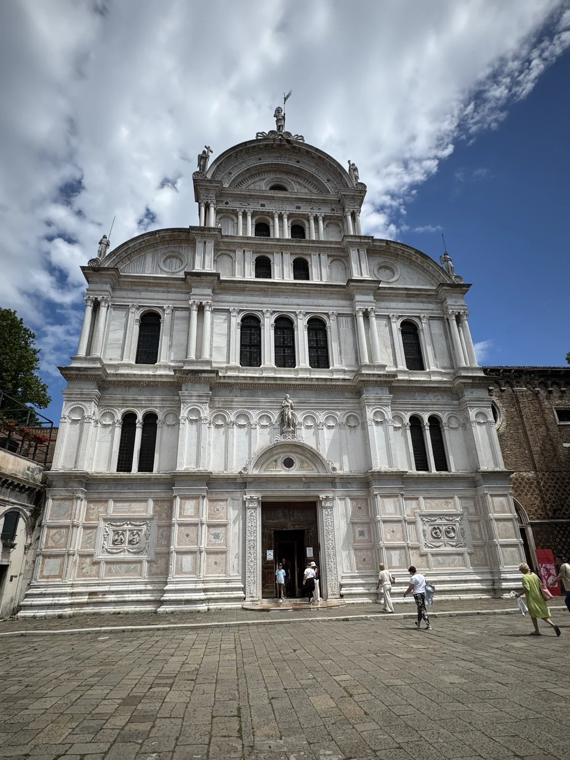 Ornate white marble façade of the Church of San Zaccaria beneath a dramatic sky.