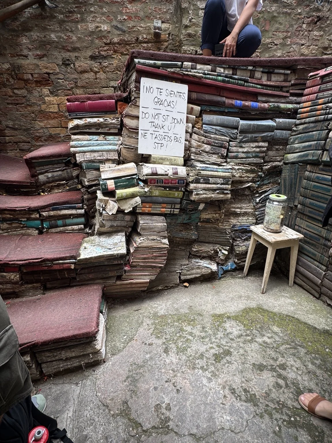 Staircase built from weathered books at Libreria Acqua Alta with a do not sit sign.