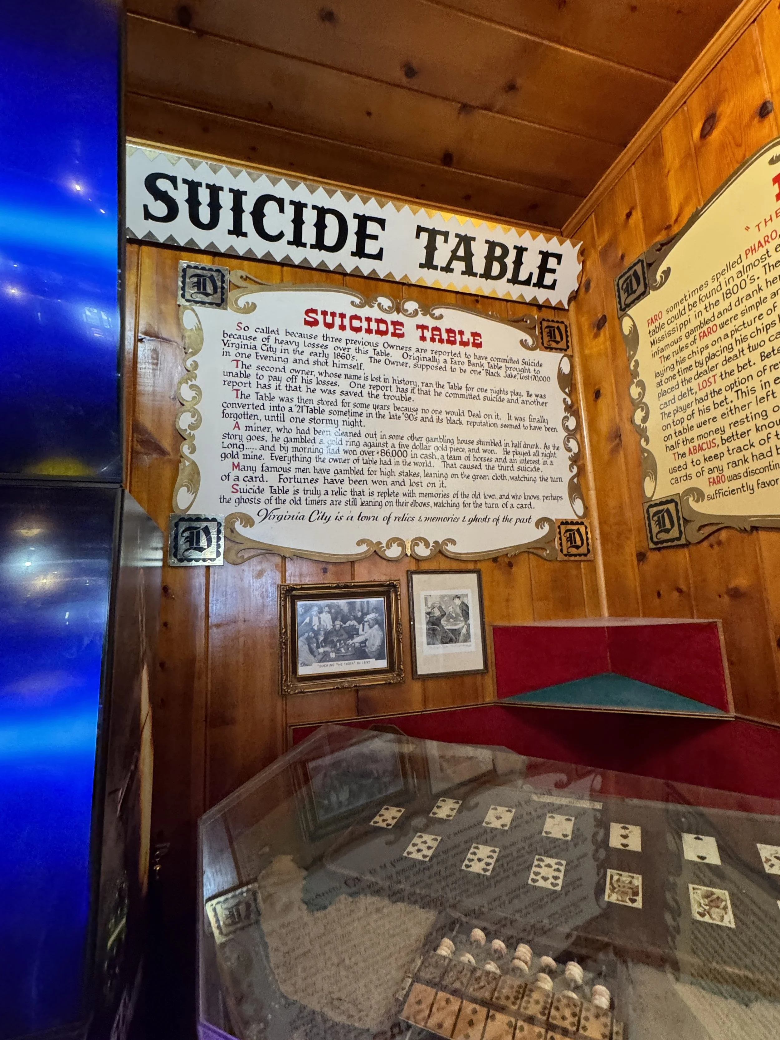 The historic Suicide Table display with playing cards and informational signs inside Virginia City’s Delta Saloon.