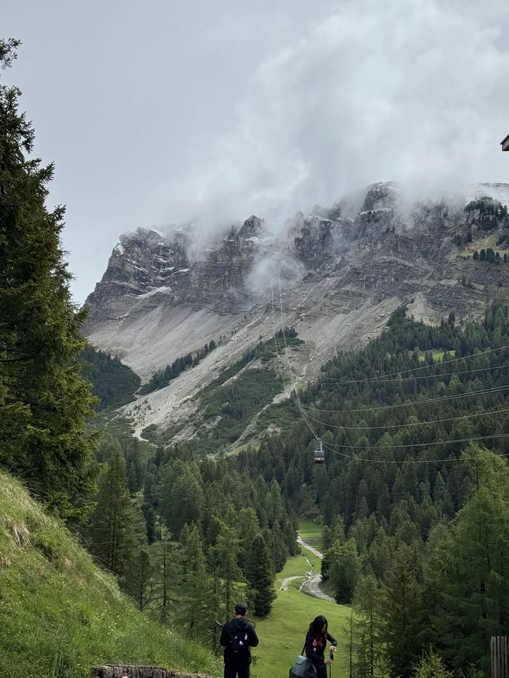 Misty Dolomite cliffs and alpine forest beside the Seceda cable car route.