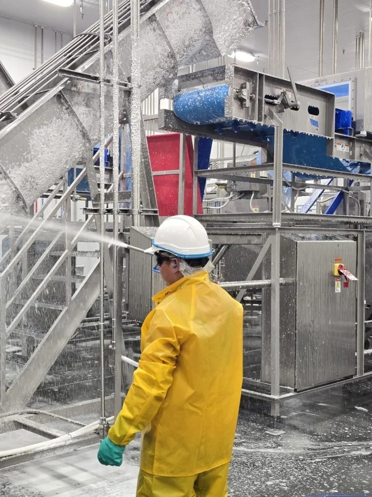 People First Sanitation crew member foaming food-plant equipment during a sanitation shift