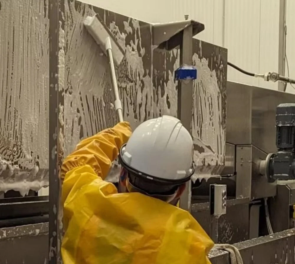People First Sanitation crew member cleaning a food-plant wall panel