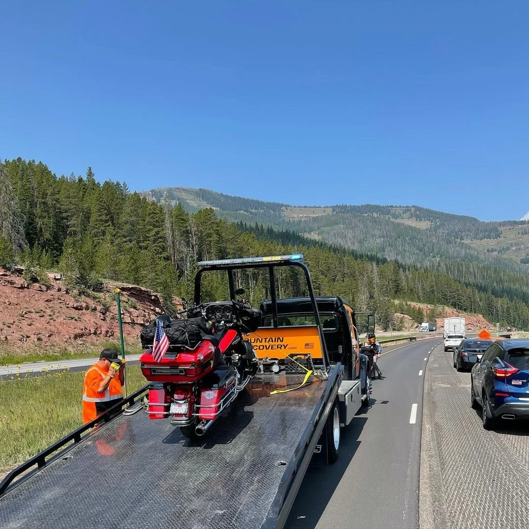 Mountain Recovery flatbed transport truck carrying a vehicle in Colorado