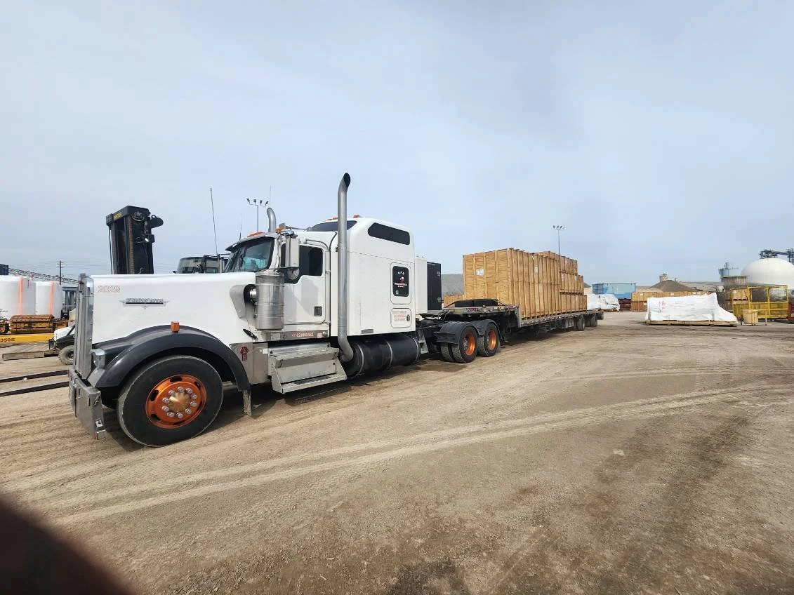 BAR Transportation white Kenworth 2029 at industrial port facility with crated cargo
