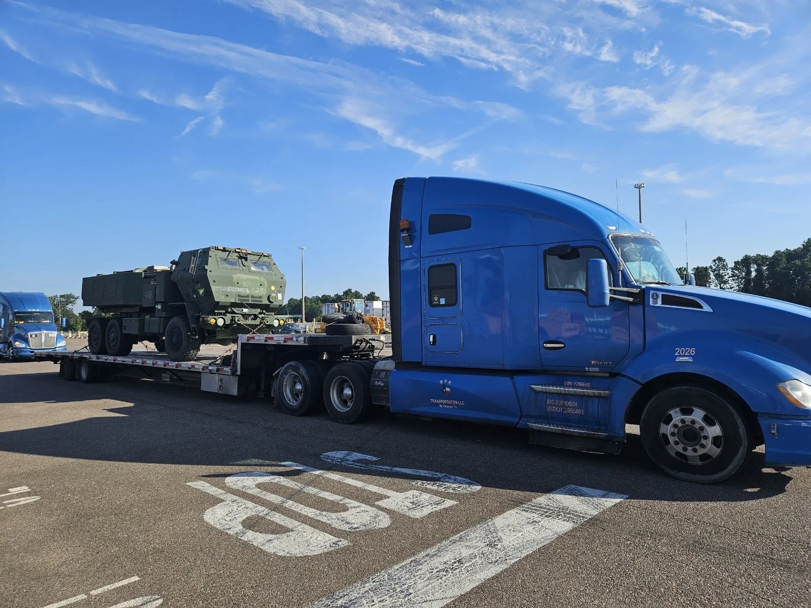 BAR Transportation blue Kenworth T680 with military vehicle on step-deck