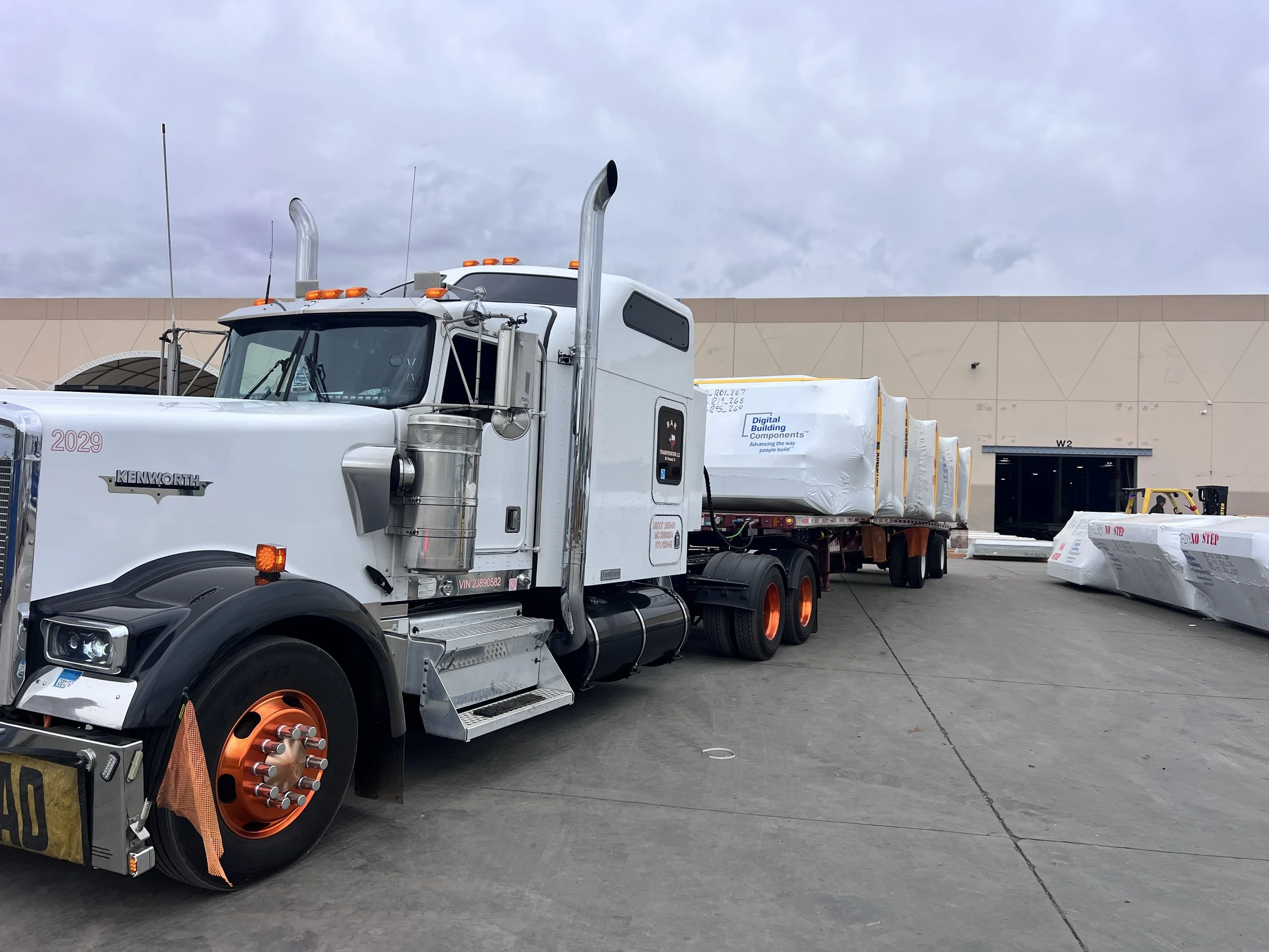 BAR Transportation white Kenworth delivering wrapped load at warehouse dock