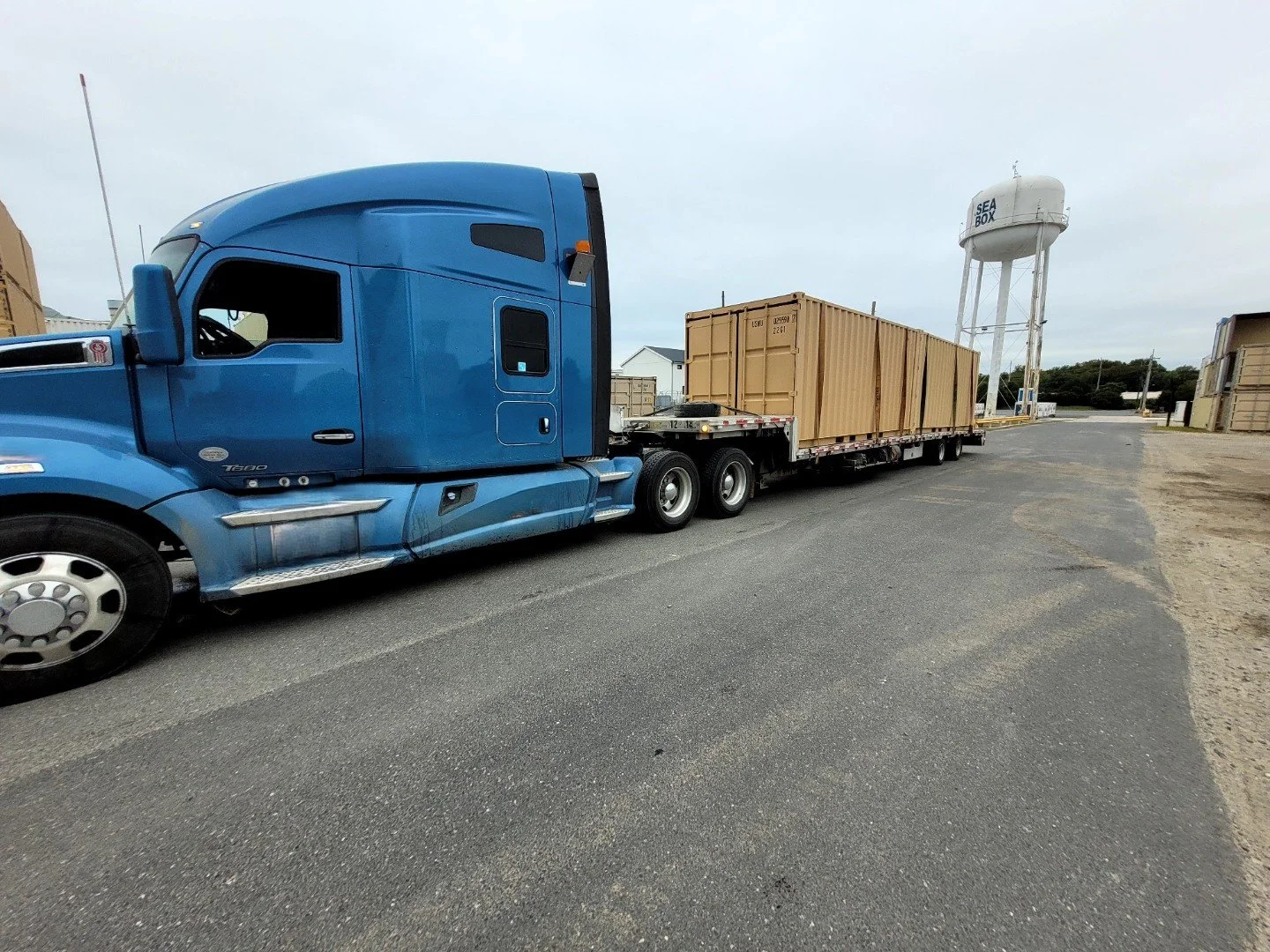 BAR Transportation blue Kenworth with crated equipment at military facility gate