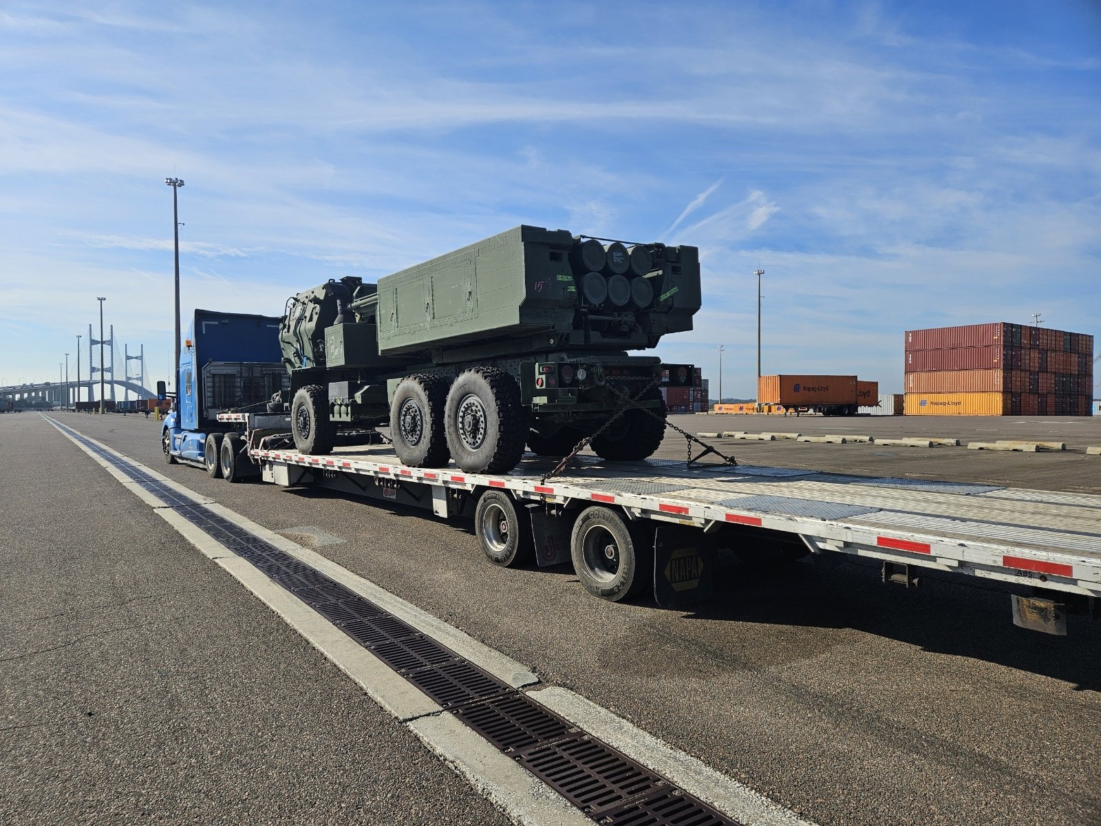 BAR Transportation white Kenworth with dual anti-aircraft artillery at naval facility at dusk