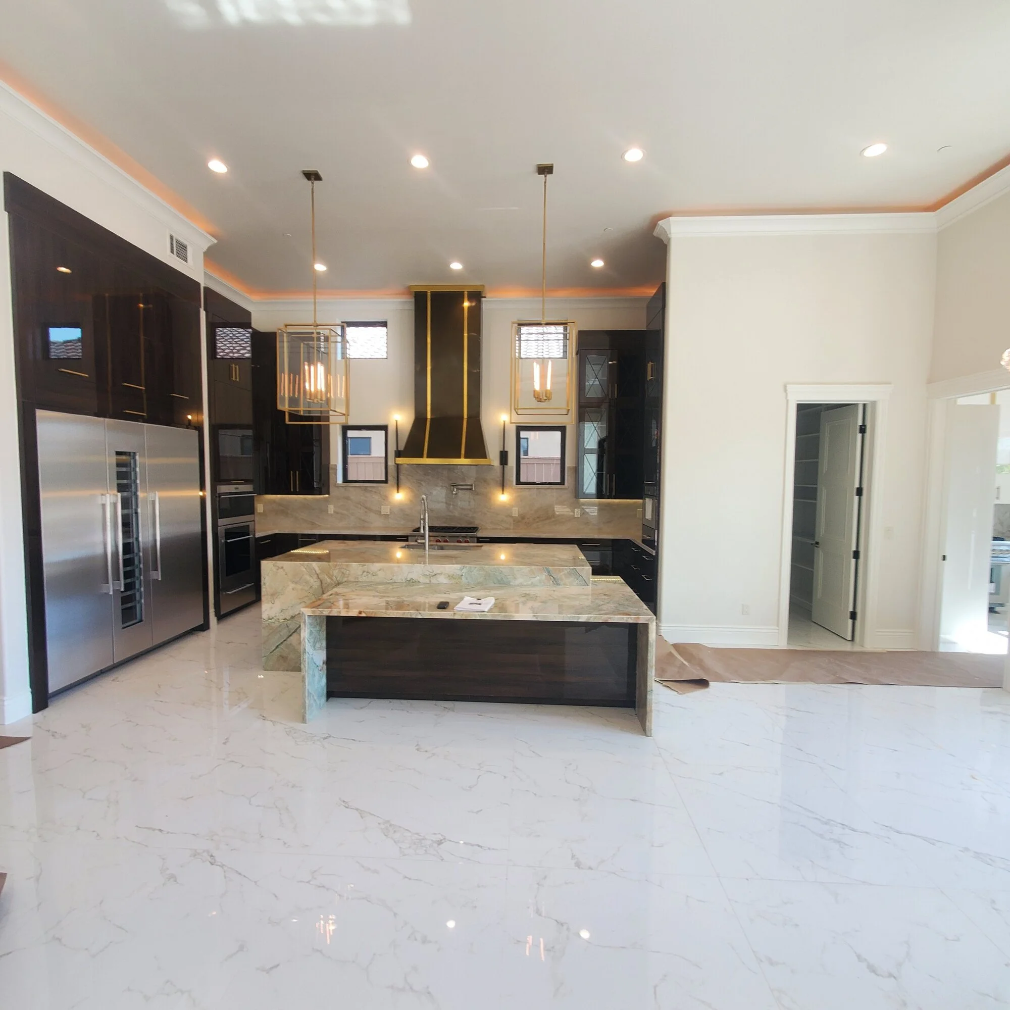 Finished kitchen with quartzite waterfall islands and brass hood — custom home, Fresno, CA