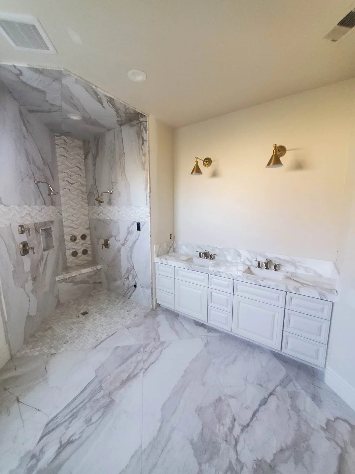 Primary bath with marble walls, double vanity, and brass fixtures — Fresno, CA