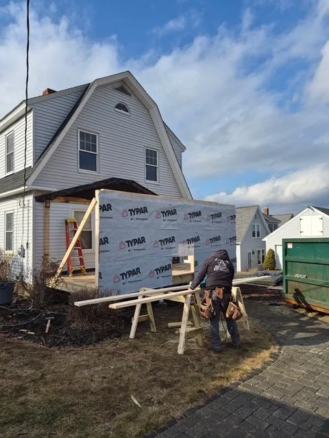 Enclosed porch framed and house-wrapped with a crew member on site in winter, York ME