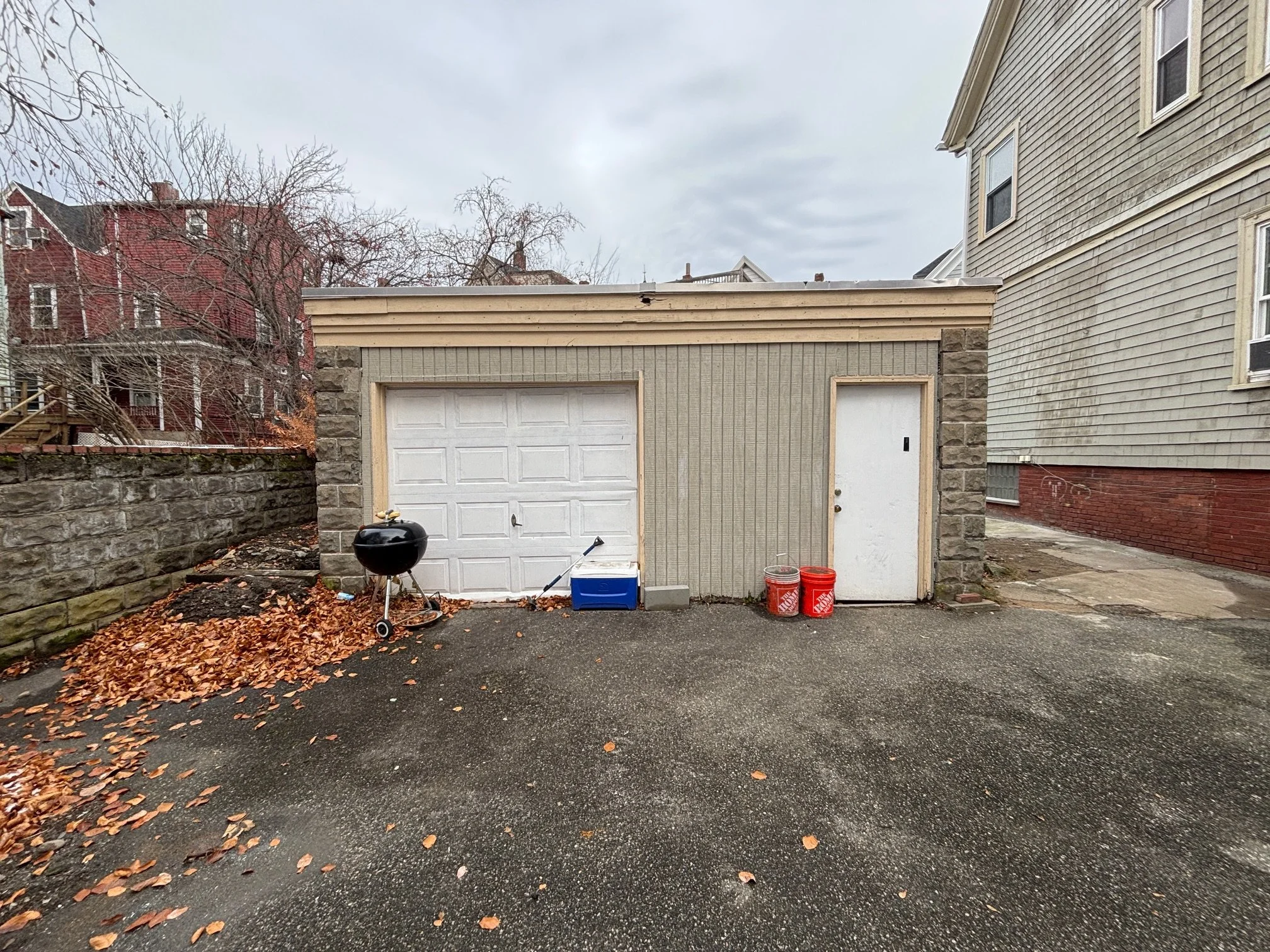 Existing single-story masonry garage with white overhead door before the ADU conversion, Somerville MA
