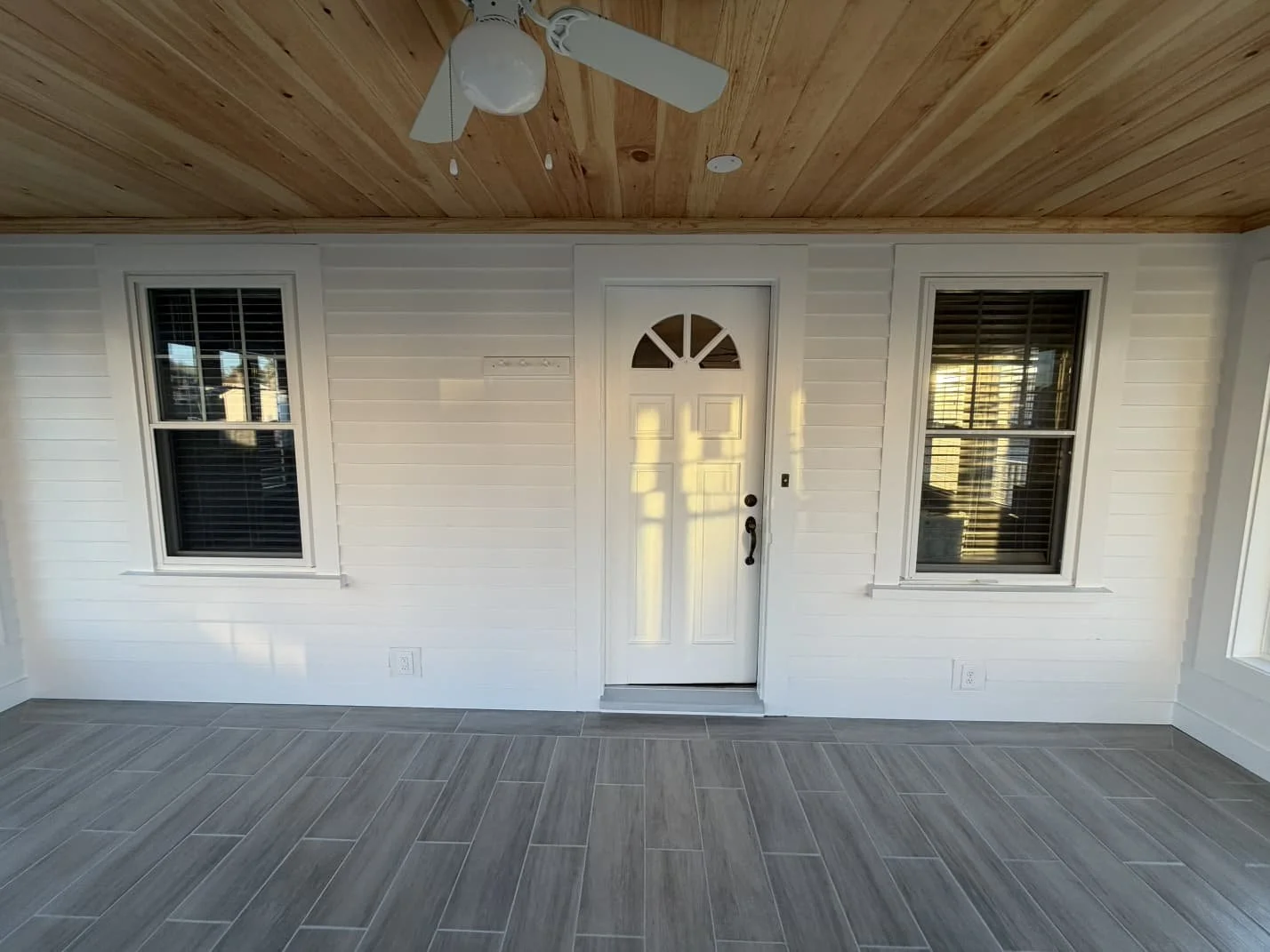 New exterior door flanked by two windows under the tongue-and-groove ceiling, York ME