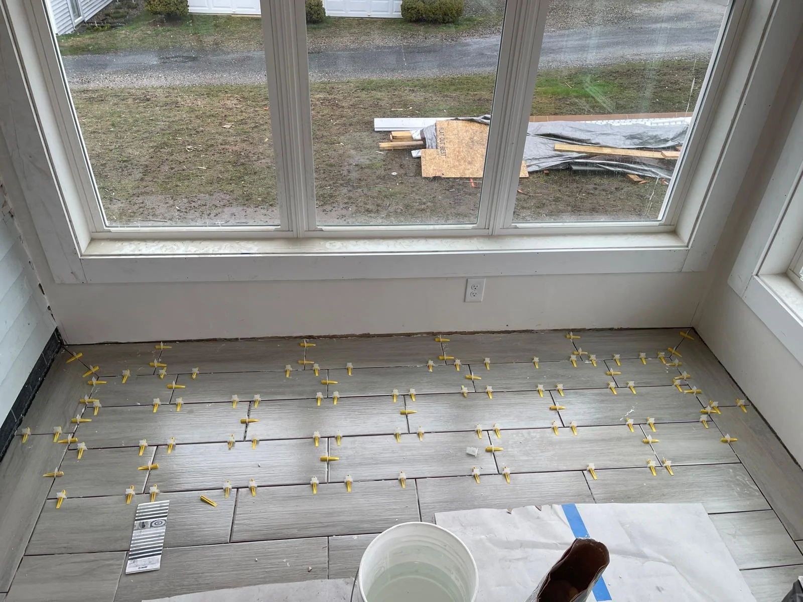 Gray wood-look plank tile set with leveling clips in the three-season porch, York ME