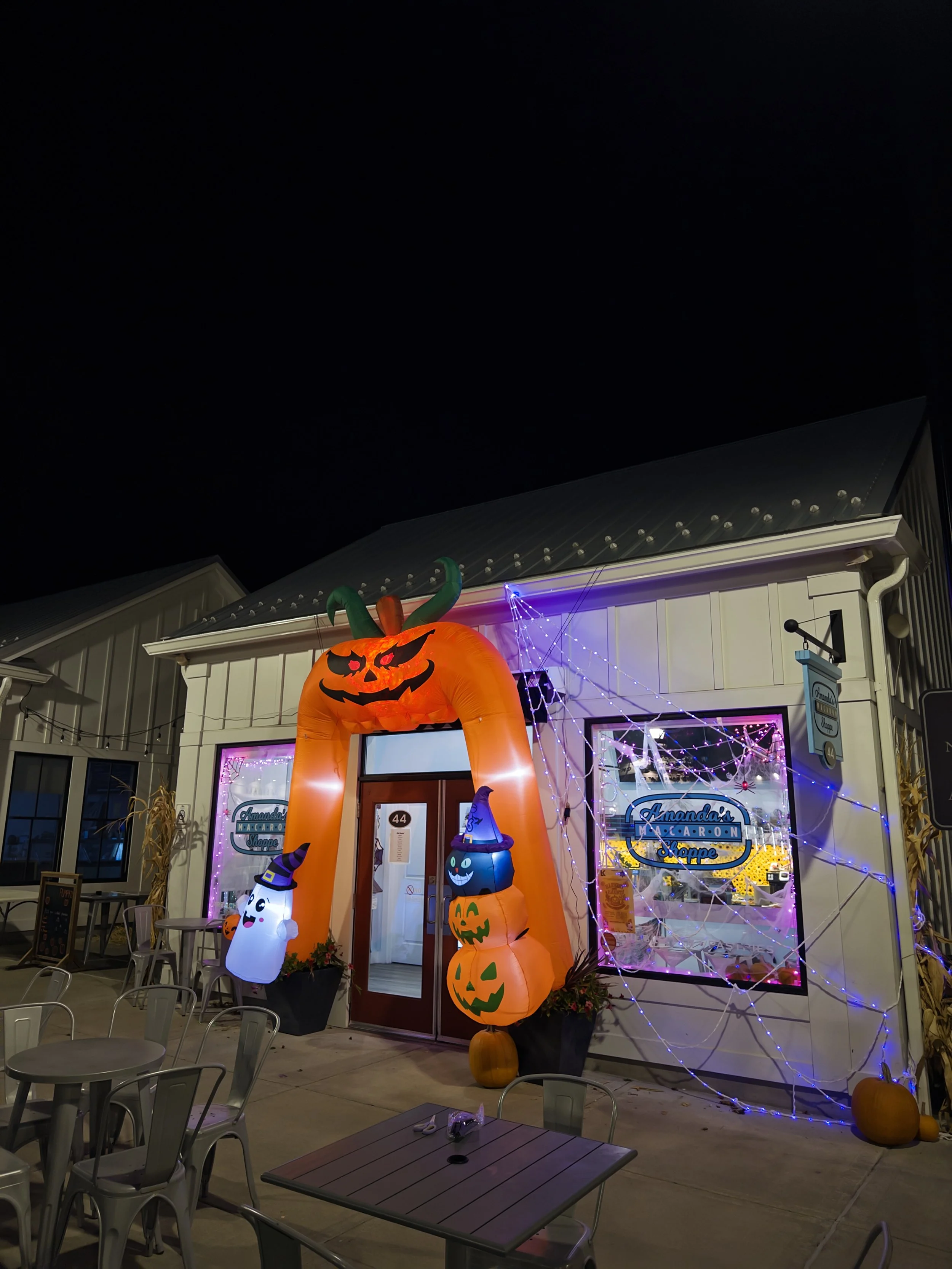 Amanda’s Macaron Shoppe glowing with a pumpkin arch and purple Halloween lights.