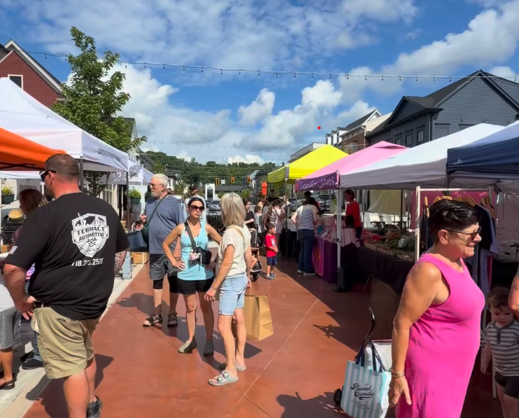 Shoppers browsing vendor tents along a busy brick walkway at Eastdale Village.