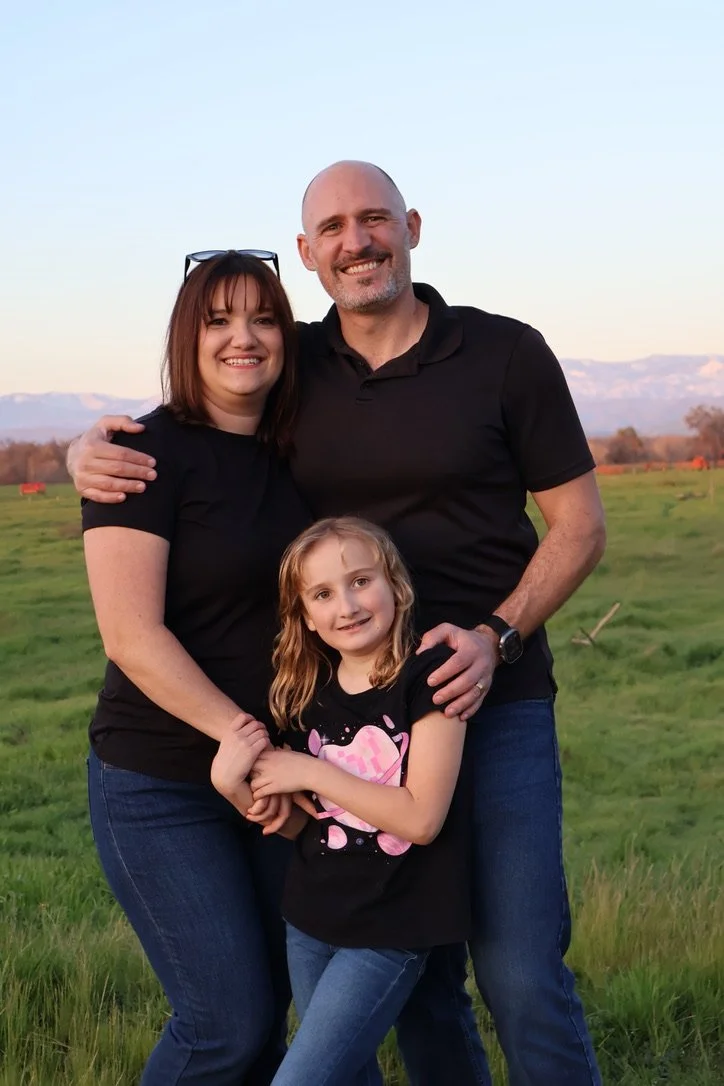Chris Gorges with his family in a green field with mountains in the distance