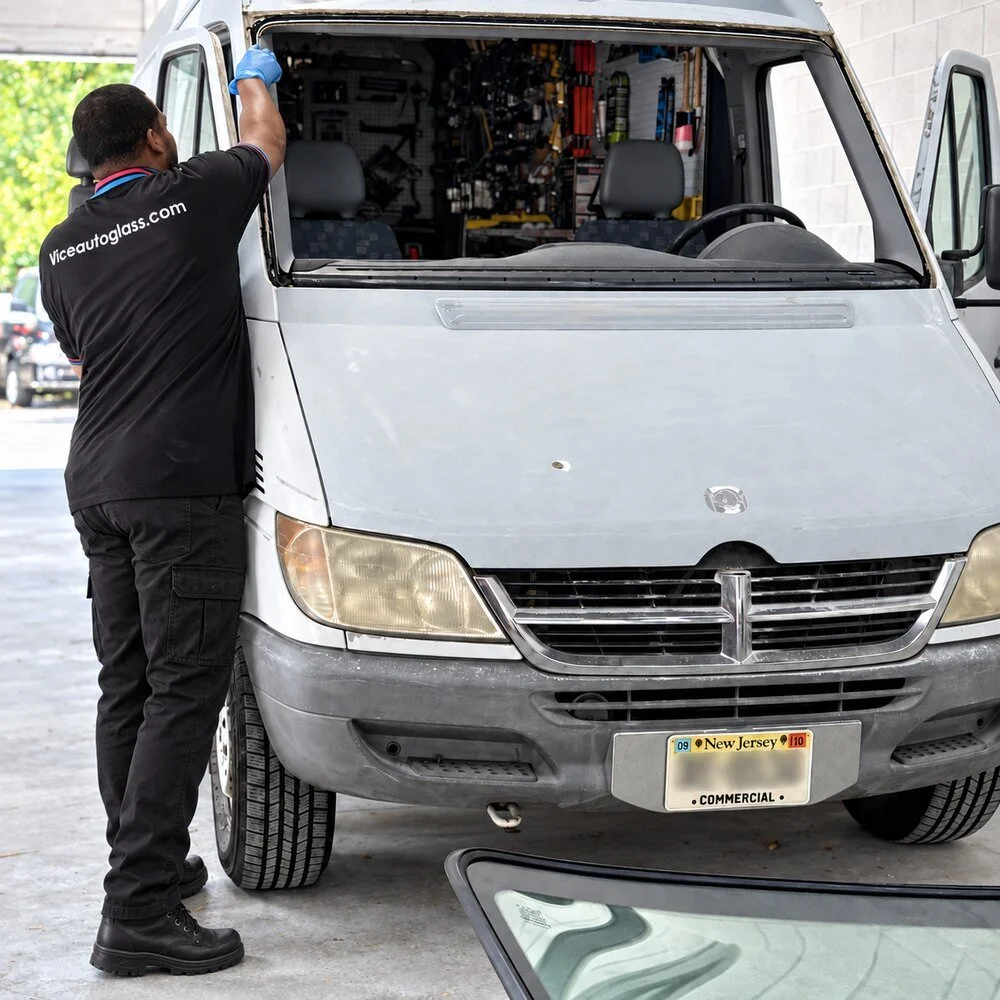 Vice Autoglass technician preparing a van windshield opening at a body shop